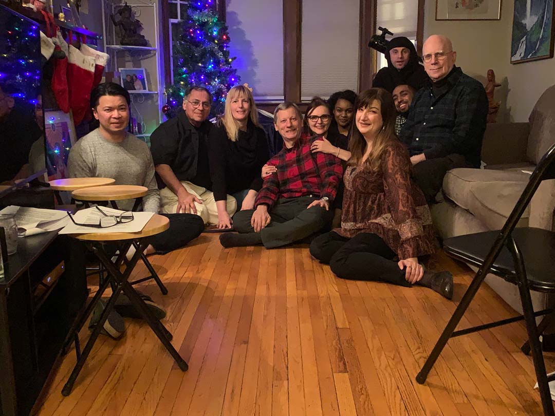 a gathering of people sitting on the floor posing for a photo together
