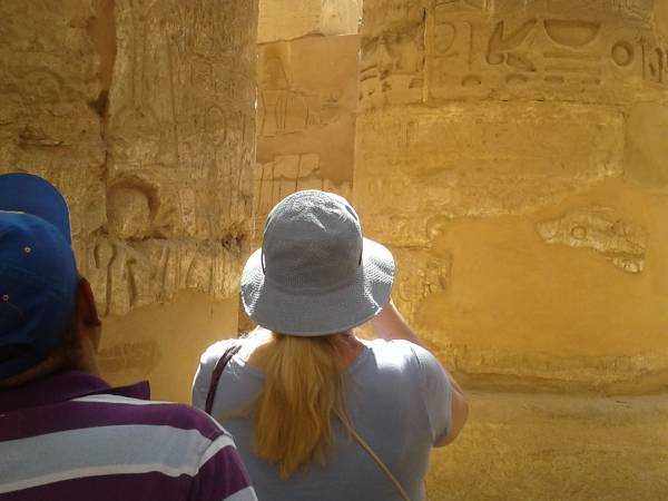 a couple standing in front of columns covered in heiroglyphics